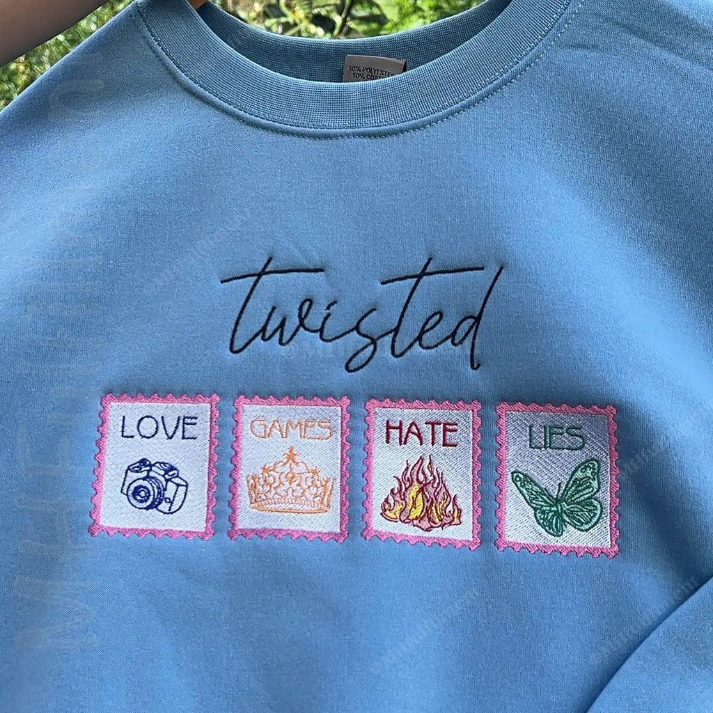 Blue sweatshirt with embroidered text and symbols on a green background