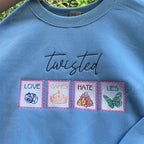 Blue sweatshirt with embroidered text and symbols on a green background