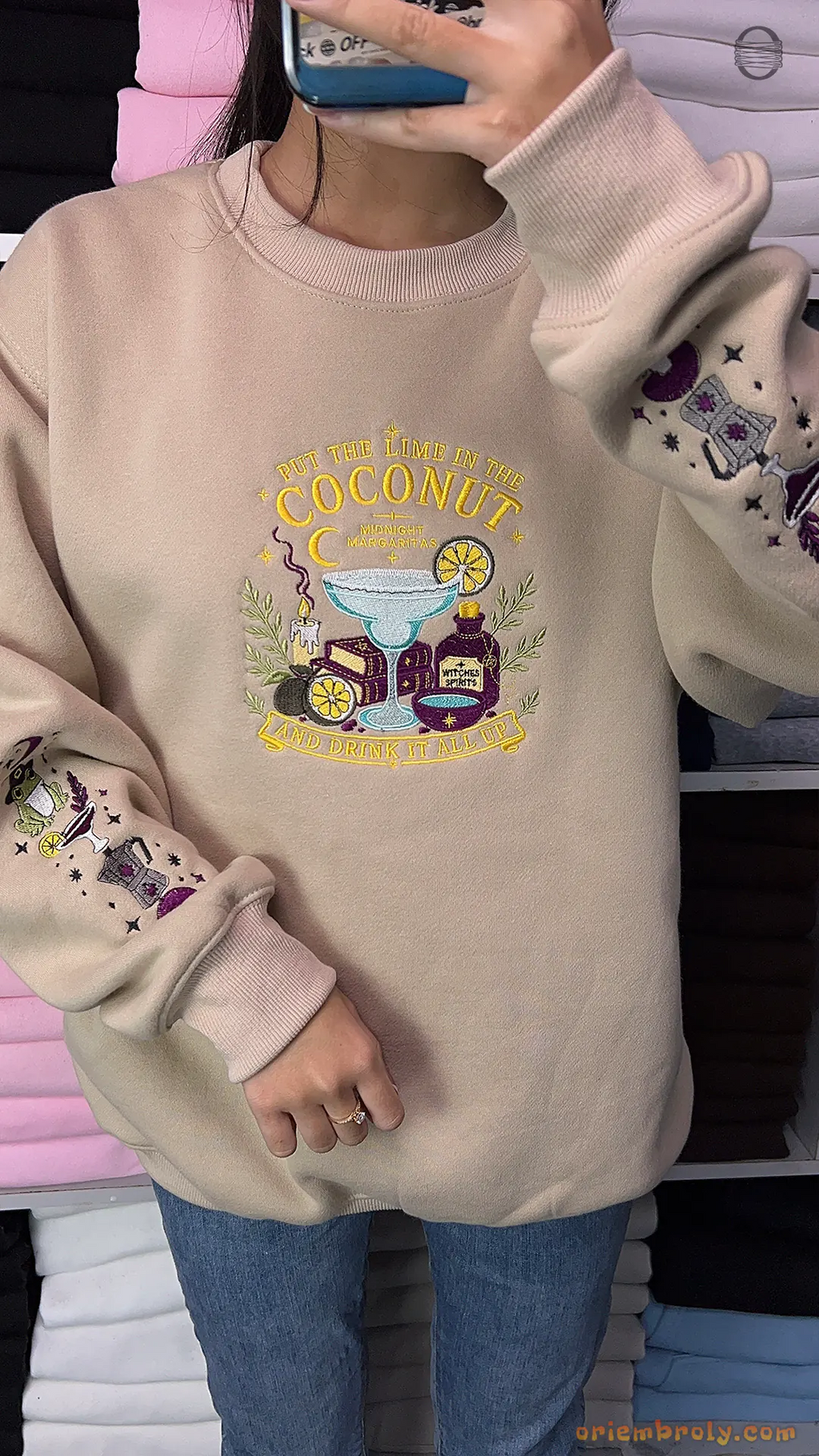 Mirror selfie of model wearing a beige Practical Magic witchy frog embroidered crewneck sweatshirt