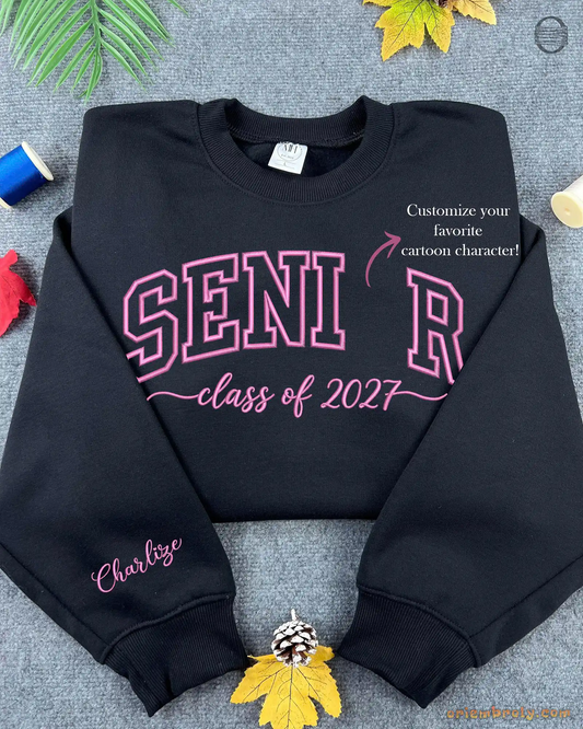 Flatlay view of a black crewneck sweatshirt embroidered with red SENIOR Class of 2027 letters and custom sleeve embroidery.