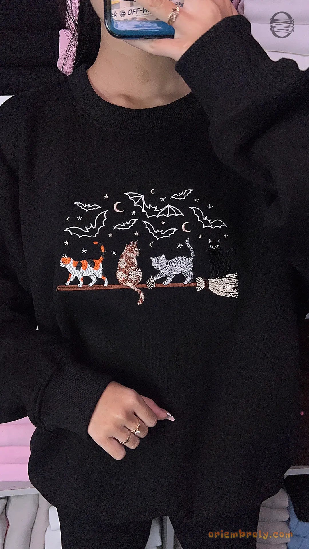 Model wearing a black Halloween embroidered crewneck sweatshirt with witchy cats and moon graphics