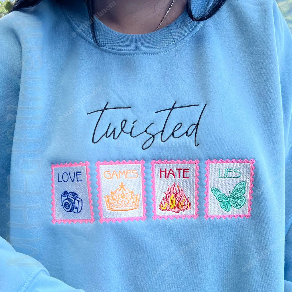 Blue sweatshirt with embroidered text and symbols on a blurred natural background