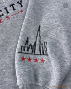 Close-up of custom sleeve embroidery featuring the Chicago city skyline and four red stars on a grey sweater sleeve