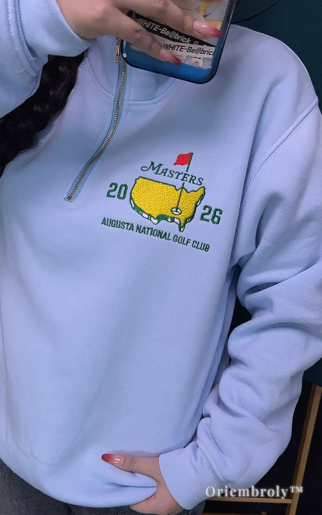 Close-up of professional satin stitch Masters embroidery on a premium pink quarter-zip. Durable thread work in vibrant green, yellow, and red on soft, heavyweight fabric