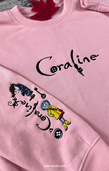 Pink sweatshirt with 'Coraline' characters and text on a plain background