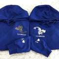 Two blue hoodies with embroidered designs on a textured surface