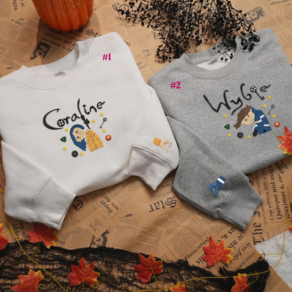 Two sweatshirts, one white and one gray, with embroidered designs on a newspaper background.