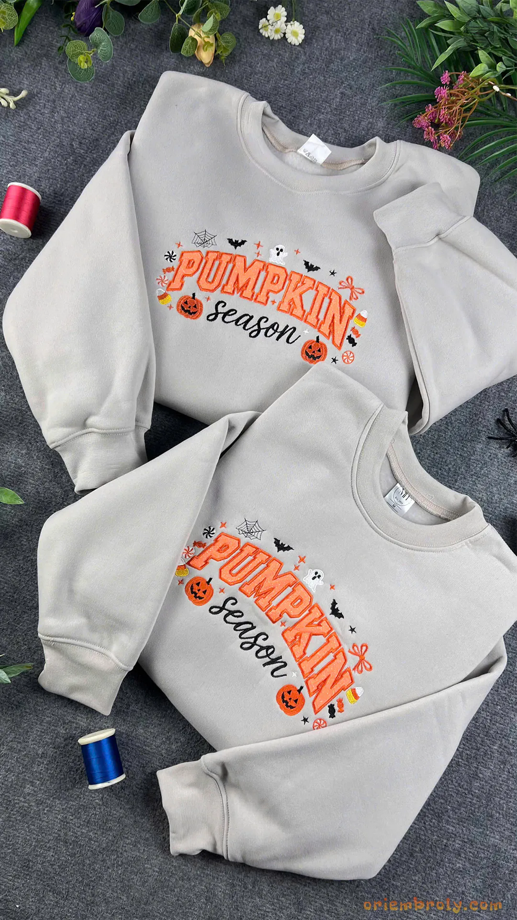 Stacked light grey Pumpkin Season embroidered crewneck sweatshirts surrounded by Halloween decor and embroidery thread spools