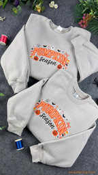 Stacked light grey Pumpkin Season embroidered crewneck sweatshirts surrounded by Halloween decor and embroidery thread spools