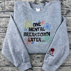 Gray sweatshirt with colorful text and designs on a wooden surface