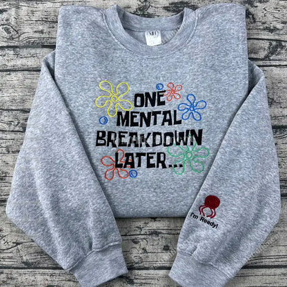Gray sweatshirt with colorful text and designs on a wooden surface