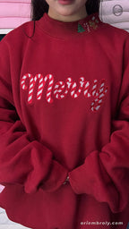 Front view of model wearing a red Christmas sweater with candy cane Merry chest embroidery and holiday collar detail