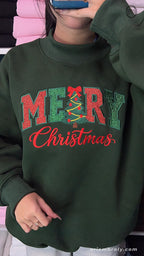 Front view of model wearing a forest green Christmas sweater with red Merry Christmas tree chest embroidery