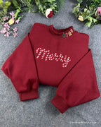 Overview of a red Christmas embroidered crewneck sweater with candy cane Merry text and holiday collar embroidery