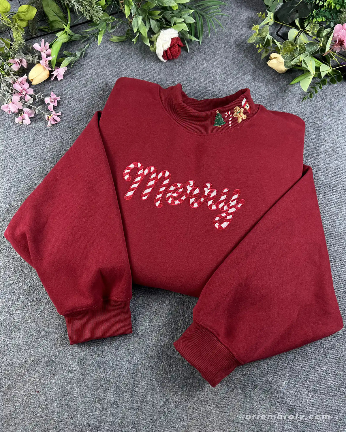Overview of a red Christmas embroidered crewneck sweater with candy cane Merry text and holiday collar embroidery