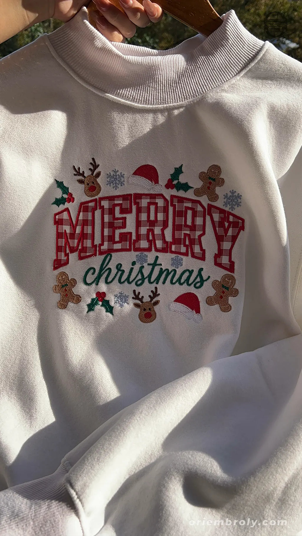 Overview of a white holiday embroidered crewneck sweater with plaid text and winter festive details