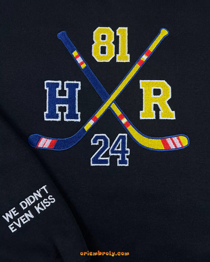 Detailed embroidery of hockey sticks and letters on crewneck