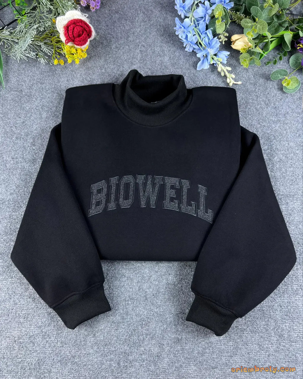 Black mock neck sweatshirt with custom dark grey Biowell embroidered lettering flat lay