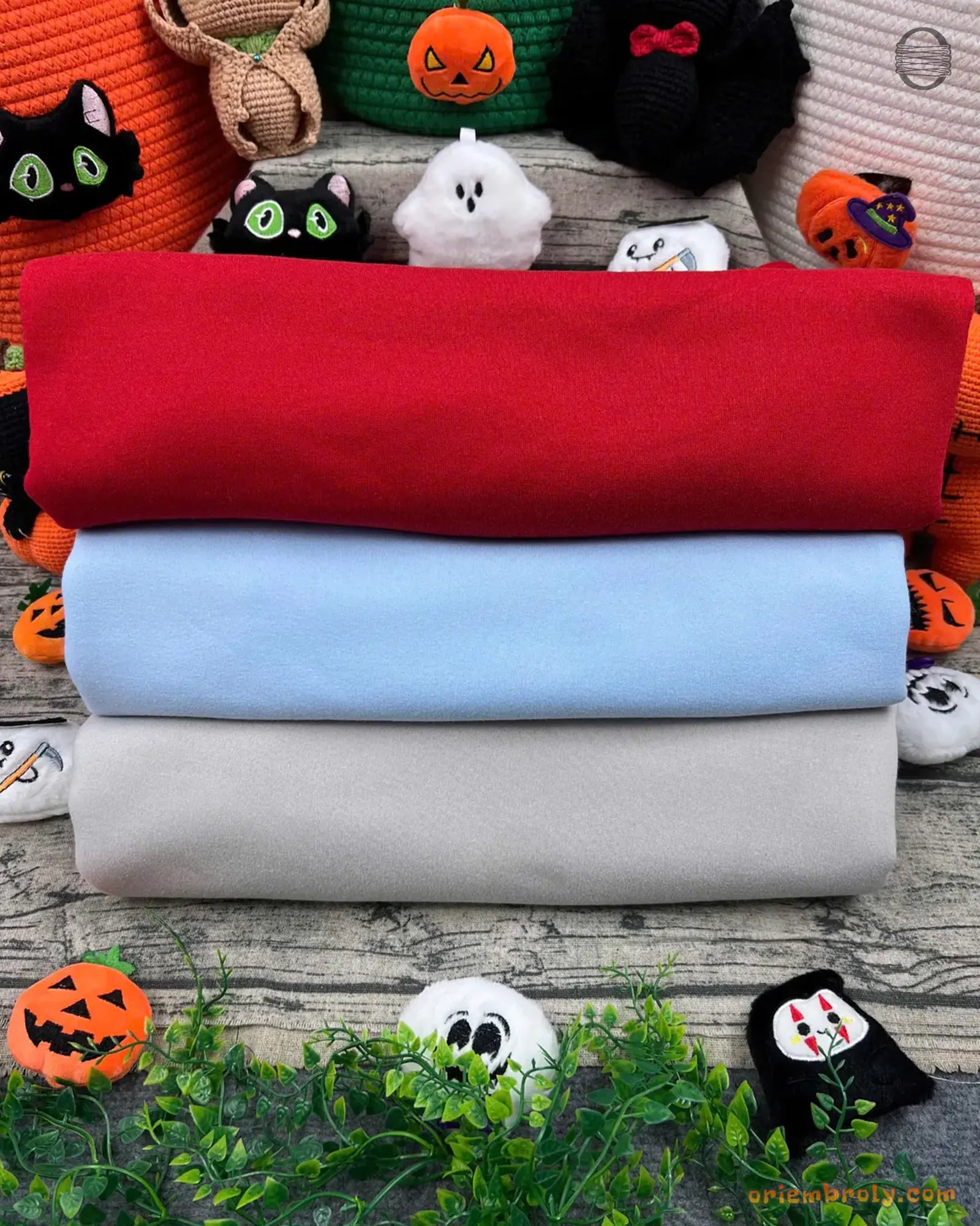 Stack of folded mock neck sweatshirts in red, light blue, and white with Halloween decor