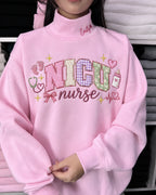 Model wearing a pink NICU nurse embroidered crewneck sweatshirt with cute pastel applique letters and personalized custom name on collar
