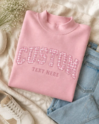 Pink mock neck pullover sweatshirt featuring custom pink glitter applique lettering flat lay