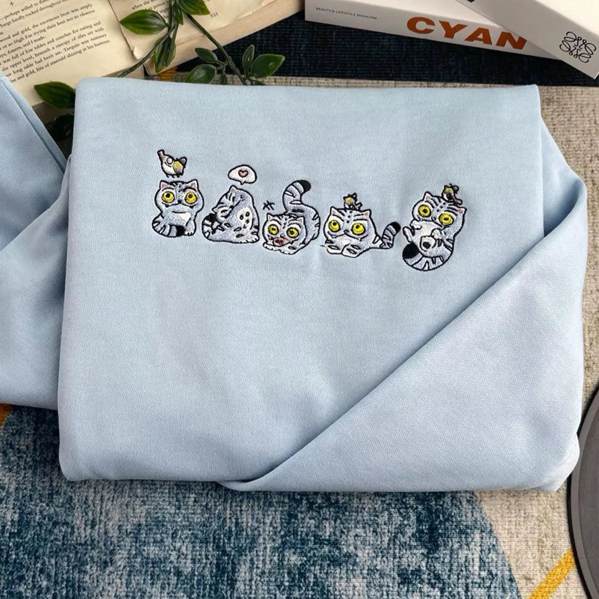 Light blue fabric with embroidered cat designs on a textured surface.