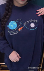 Close-up of high-density embroidery on a navy fleece sweatshirt showing the Artemis II mission path from Earth to Moon. Premium textured satin stitching for long-lasting quality