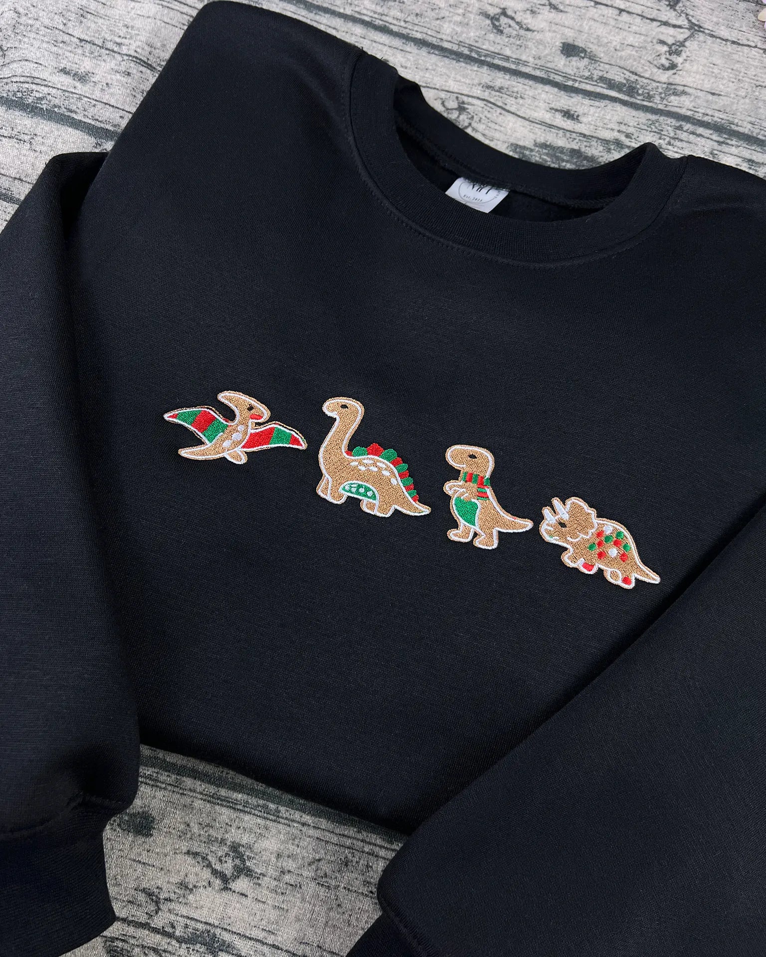 Holiday-themed dinosaur sweatshirt with festive Santa hat embroidery