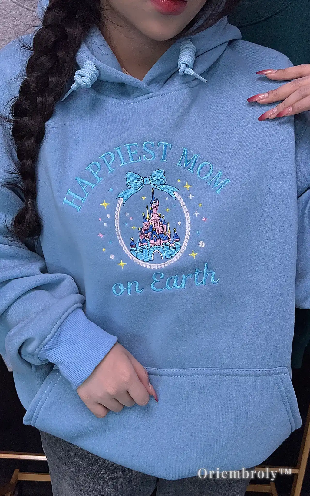 Stylish light blue hoodie with "Happiest Mom on Earth" and a magical castle embroidery. Ideal for a cozy and cute Main Street USA outfit during a Disney vacation
