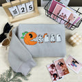 Gray sweatshirt with Halloween-themed design on a surface with decorative items.