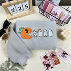 Gray sweatshirt with Halloween-themed design on a surface with decorative items.
