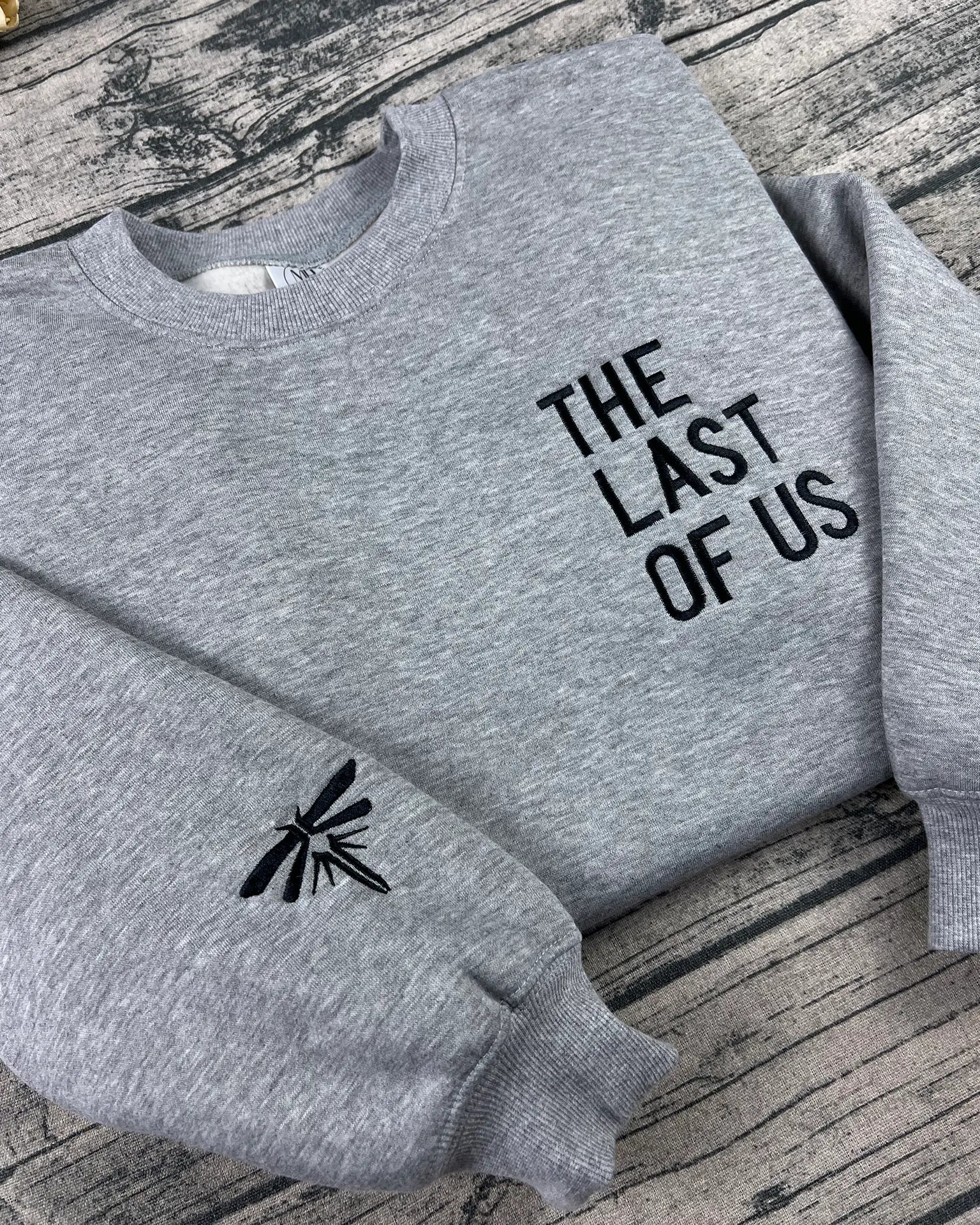 Premium black-thread embroidery of THE LAST OF US text with Firefly logo