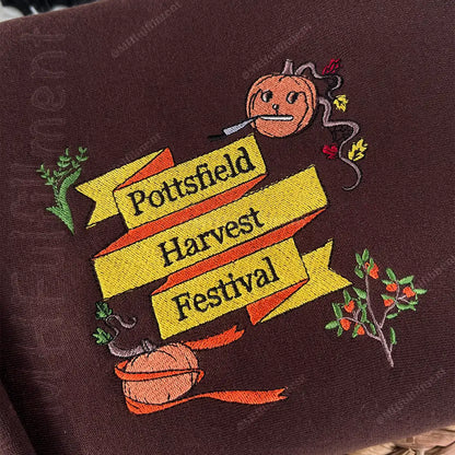 Embroidered design of a pumpkin with text 'Pottsfield Harvest Festival' on a brown fabric background.