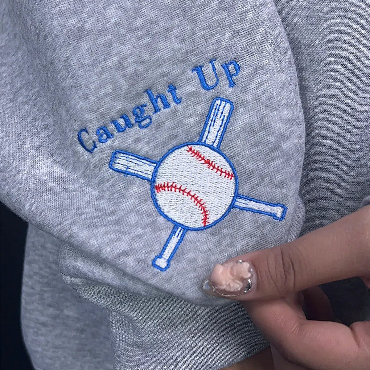 Gray sweatshirt with 'Caught Up' and baseball graphic design.