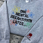 Gray sweatshirt with colorful text and flower graphics on a wooden surface
