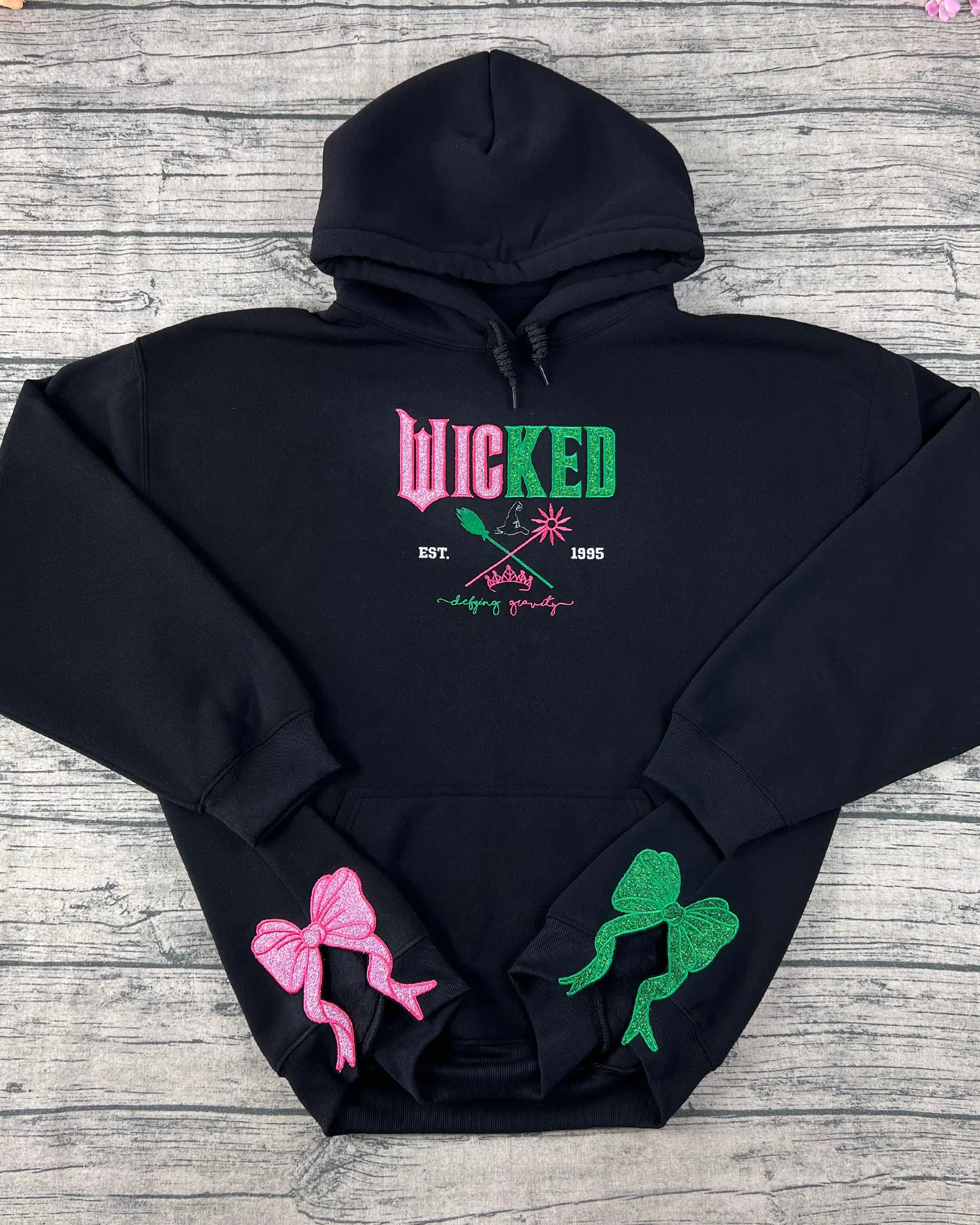 Embroidered Wicked sweatshirt hoodie featuring Defy Gravity applique with Glinda and Elphaba design. Perfect Halloween witch gift for her and Wizard of Oz fans.
