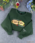 Overview flat lay of forest green Lukes Diner embroidered crewneck sweater with custom sleeve bow embroidery