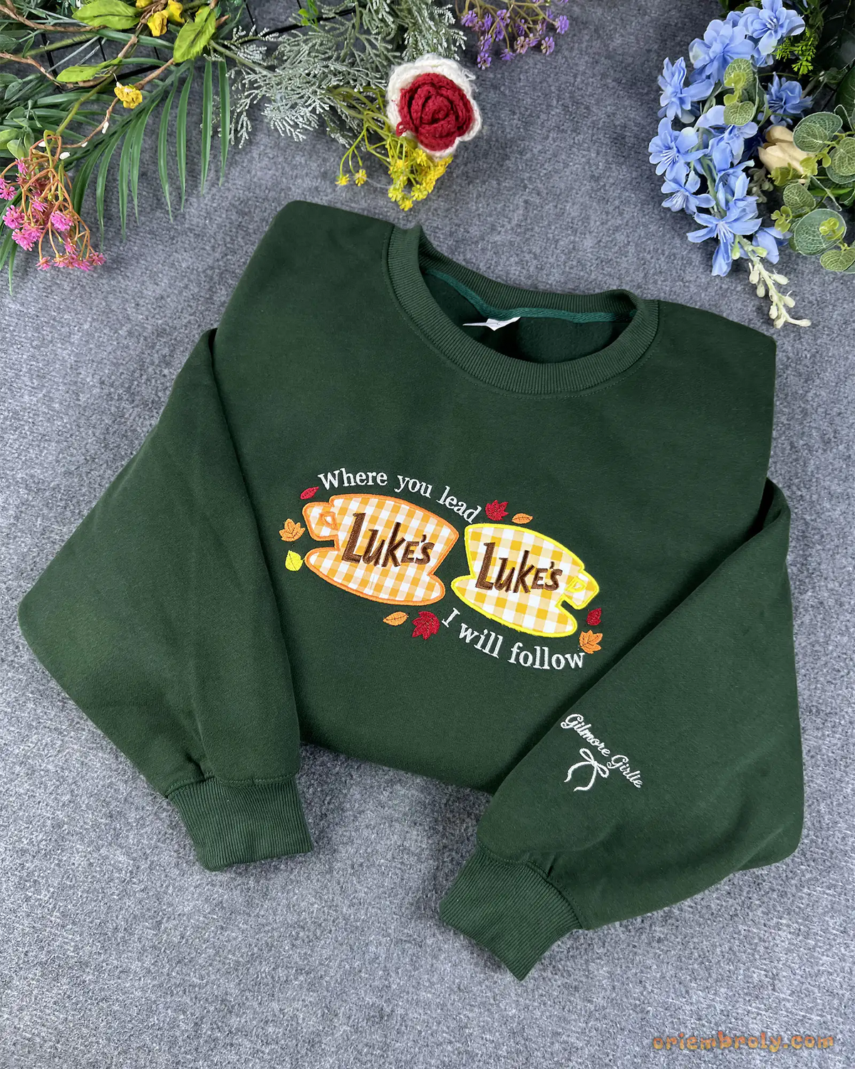 Overview flat lay of forest green Lukes Diner embroidered crewneck sweater with custom sleeve bow embroidery