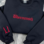 Black sweatshirt with red 'Ubermensch' text on a wooden surface