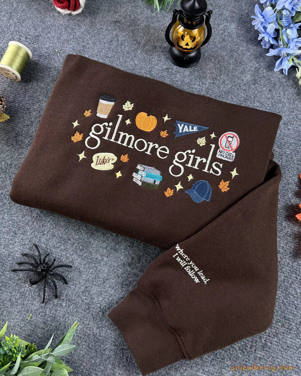 Folded brown Gilmore Girls crewneck sweater with cozy fall aesthetic decor and sleeve embroidery detail