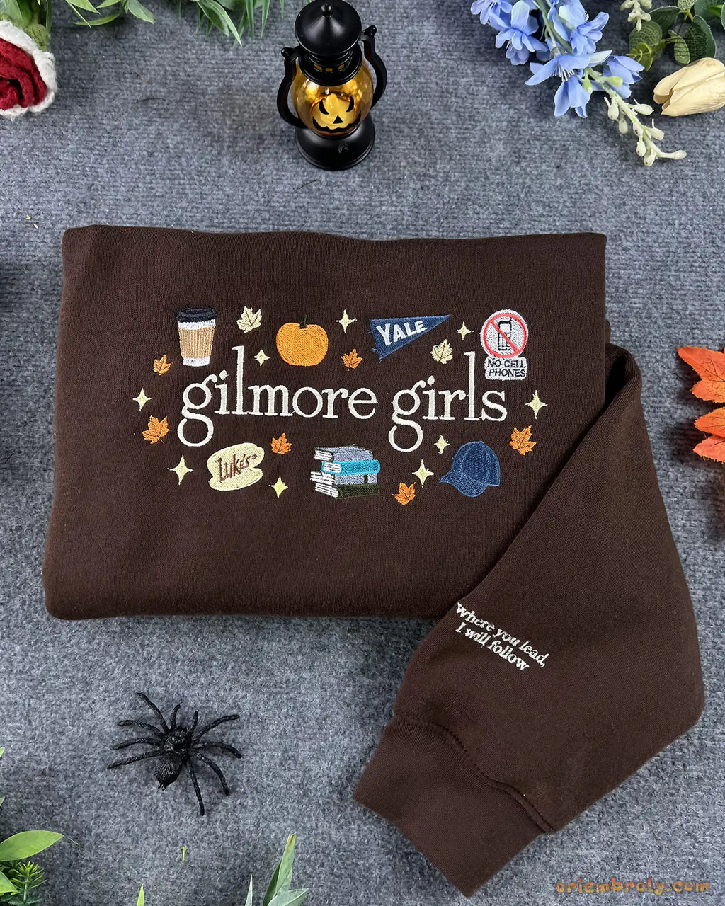 Flat lay of a brown Gilmore Girls embroidered sweatshirt with Luke's diner coffee cup, pumpkin, and autumn details