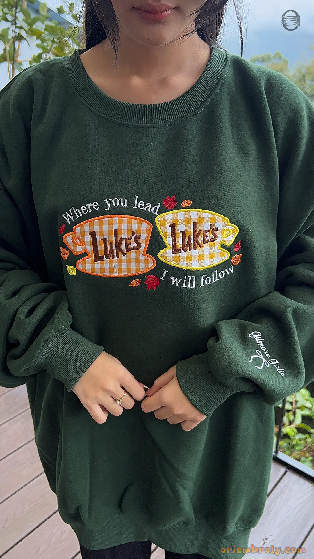 Front view try-on fit of model wearing a forest green Gilmore Girls Lukes Diner embroidered crewneck sweater