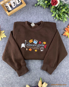 Flat lay of a chocolate brown Gilmore Girls embroidered sweatshirt featuring Stars Hollow graphics and fall leaves