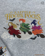 Detailed view of colorful embroidery on a gray sweatshirt featuring flying witches, full moon, bats, and stars.