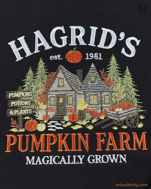 Close-up of fine embroidery on a black sweatshirt featuring Hagrid's Pumpkin Farm text, wooden cabin, pine trees, and pumpkins.