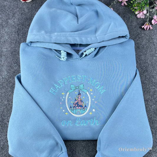 Premium light blue hoodie featuring "Happiest Mom on Earth" embroidery with a detailed Disney princess castle and bow. The perfect matching outfit for a family trip to Disneyland or Disney World