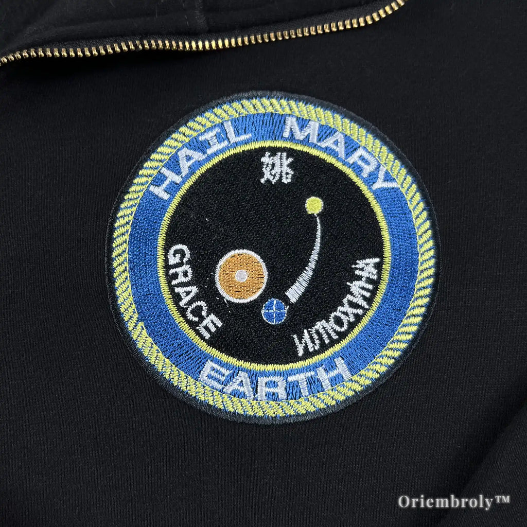 Close-up of heavyweight black quarter-zip with vibrant satin-stitched NASA-style mission patches. Durable, premium thread work designed for long-lasting comfort and style