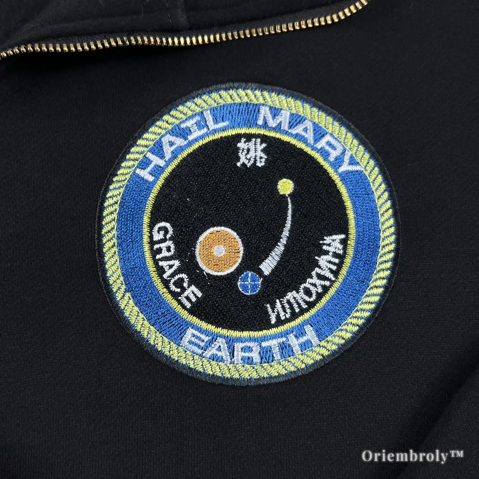 Close-up of heavyweight black quarter-zip with vibrant satin-stitched NASA-style mission patches. Durable, premium thread work designed for long-lasting comfort and style