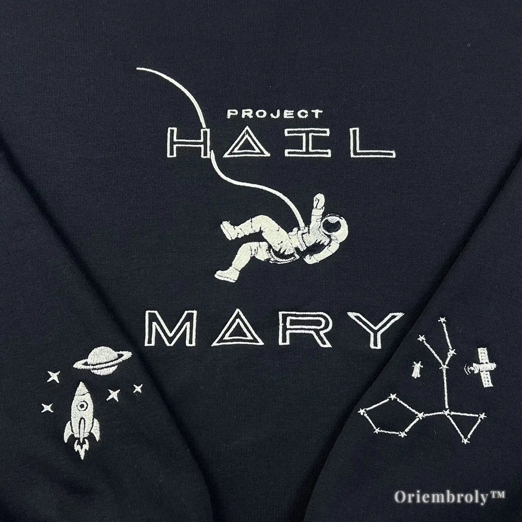 Close-up of a heavyweight black sweatshirt with premium white satin-stitched astronaut and "Project Hail Mary" title. Durable, high-density thread work designed for a premium, textured finish and long-lasting wear
