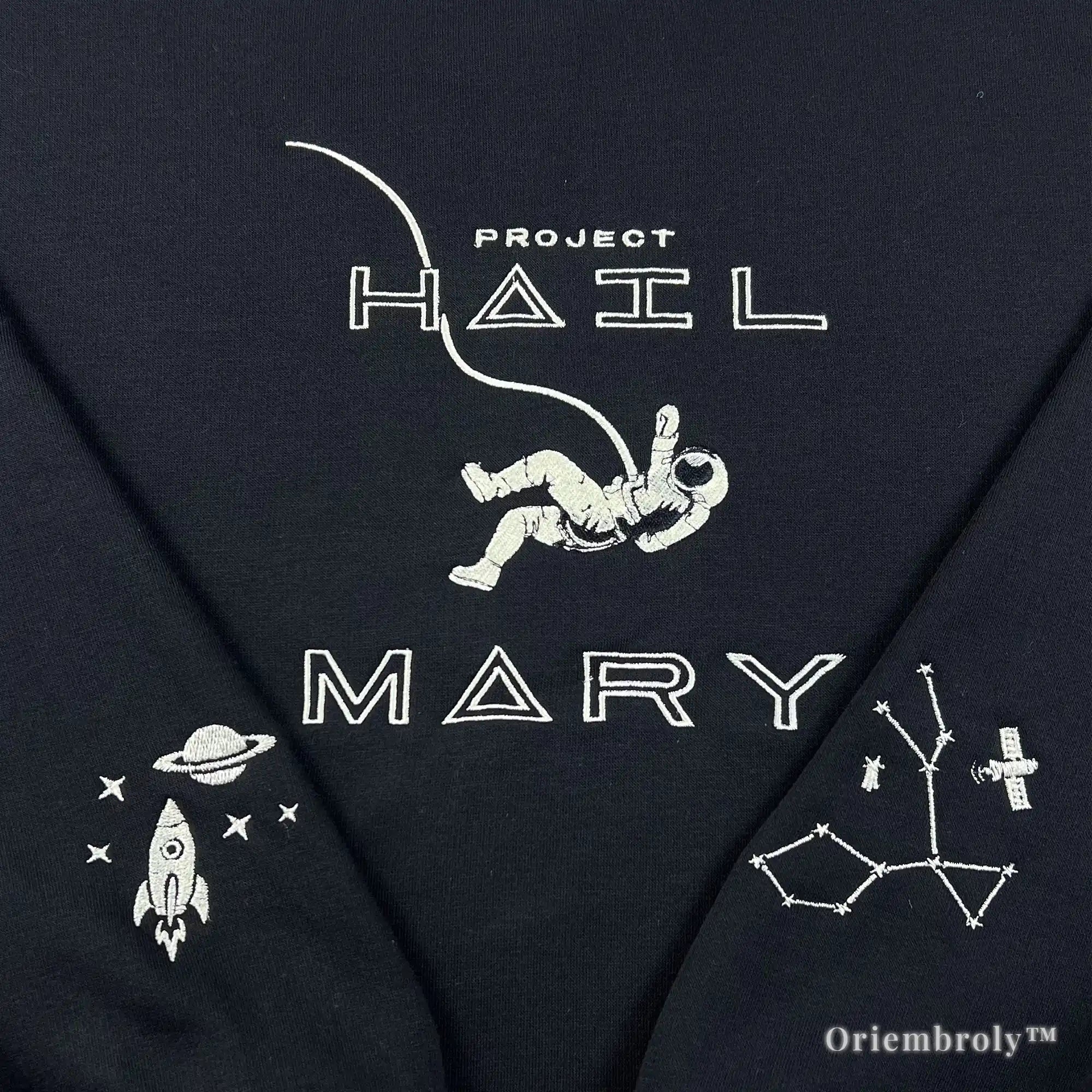 Close-up of a heavyweight black sweatshirt with premium white satin-stitched astronaut and "Project Hail Mary" title. Durable, high-density thread work designed for a premium, textured finish and long-lasting wear
